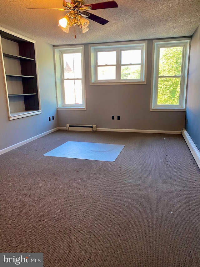 carpeted spare room featuring ceiling fan, a textured ceiling, baseboard heating, and built in shelves