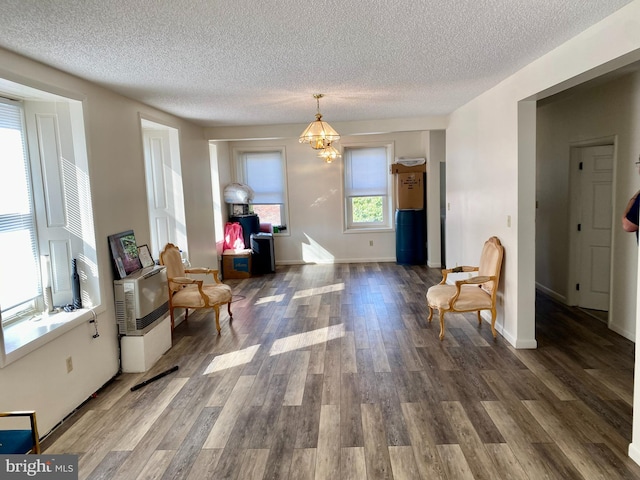 living area with a notable chandelier, dark hardwood / wood-style floors, and a textured ceiling