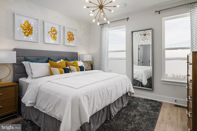 bedroom with light hardwood / wood-style flooring, multiple windows, and a water view