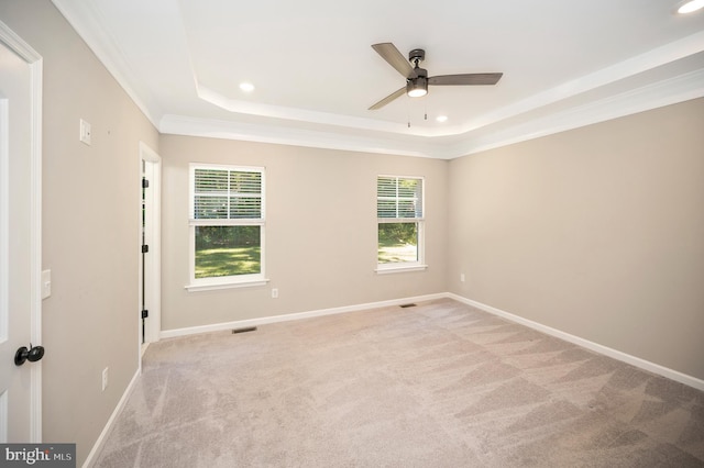 carpeted empty room featuring ceiling fan, a tray ceiling, and ornamental molding