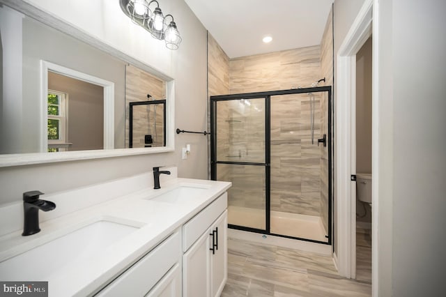 bathroom featuring toilet, vanity, and a shower with shower door