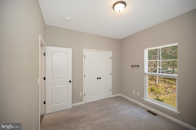 unfurnished bedroom featuring light colored carpet and a closet