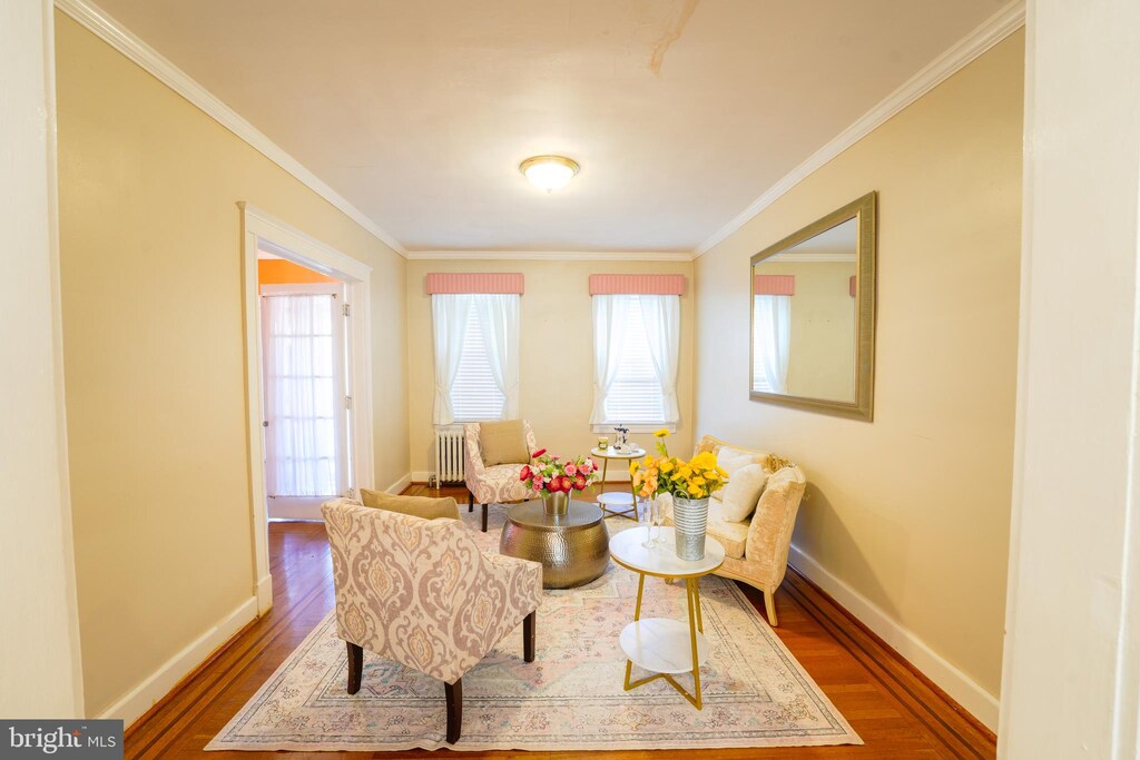 living area featuring crown molding, radiator, and wood-type flooring