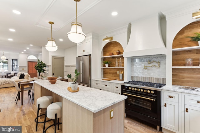 kitchen featuring a kitchen island, light stone countertops, custom range hood, white cabinets, and premium appliances