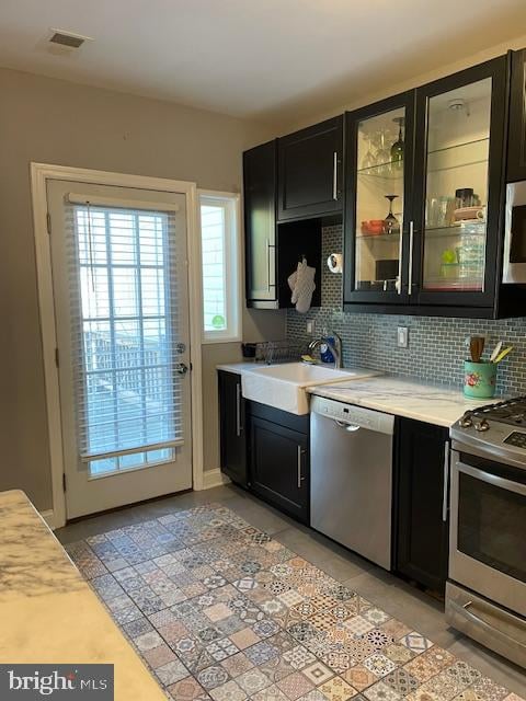 kitchen with light tile patterned floors, stainless steel appliances, backsplash, and sink