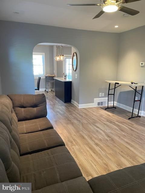 living room featuring ceiling fan with notable chandelier and hardwood / wood-style flooring