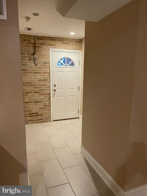 foyer entrance with brick wall and light tile patterned floors