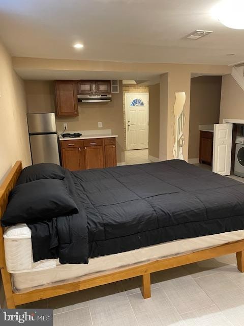 bedroom featuring washer / clothes dryer and stainless steel fridge