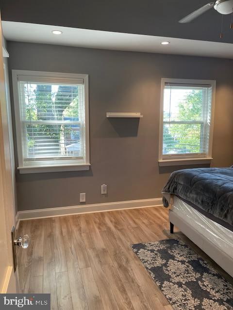 bedroom featuring hardwood / wood-style flooring, multiple windows, and ceiling fan