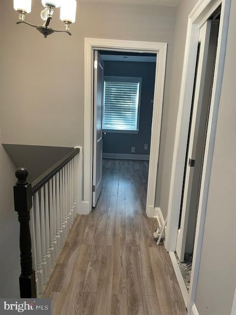 hallway with hardwood / wood-style flooring and a notable chandelier