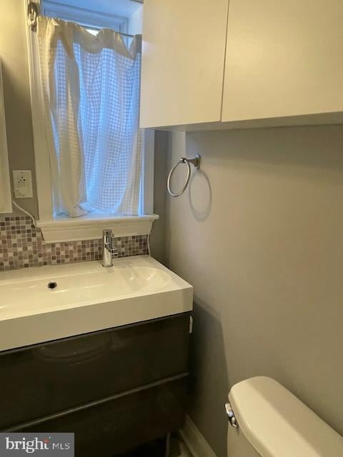 bathroom featuring vanity, toilet, and decorative backsplash