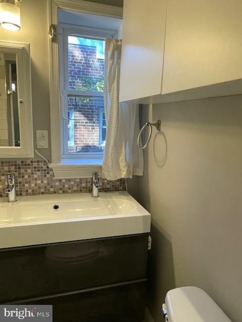 bathroom featuring backsplash, vanity, and toilet