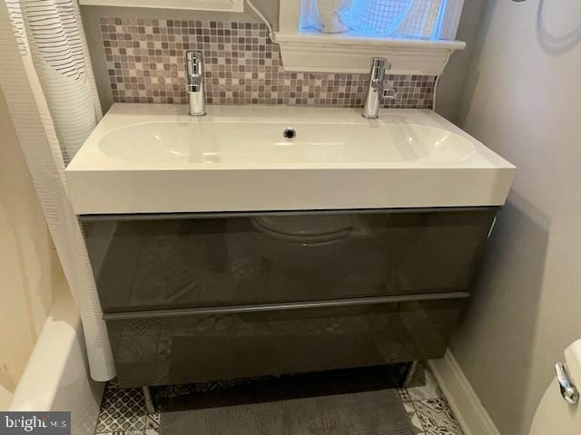 bathroom with toilet, vanity, and tasteful backsplash