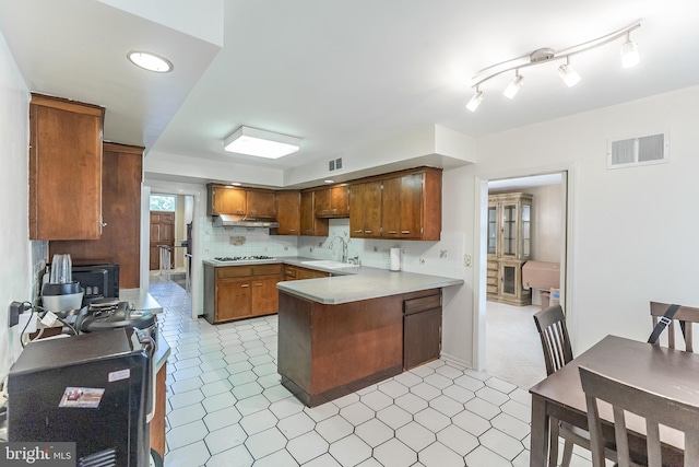 kitchen featuring white gas cooktop, sink, backsplash, and kitchen peninsula