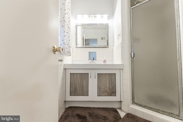 bathroom featuring a shower with shower door and vanity