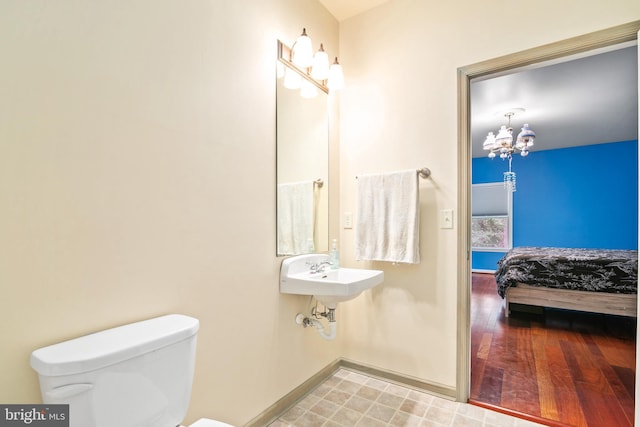 bathroom featuring toilet, hardwood / wood-style flooring, sink, and a chandelier