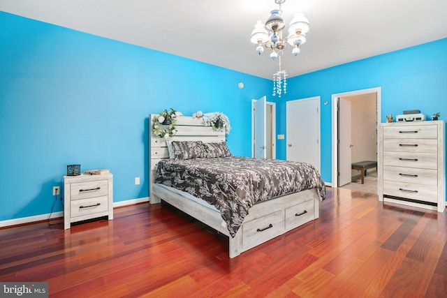 bedroom with dark hardwood / wood-style floors and an inviting chandelier