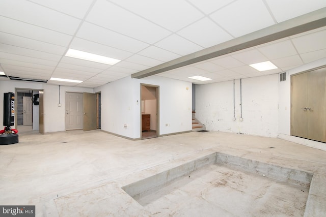 basement with water heater and a paneled ceiling