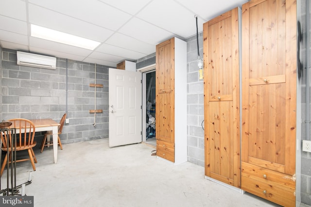 basement with a wall unit AC and a paneled ceiling