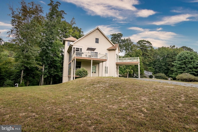 rear view of house with a wooden deck and a lawn