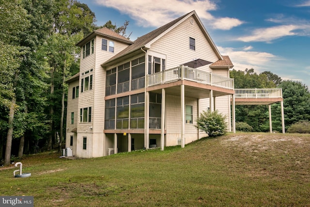 back of property featuring a yard, a sunroom, and a deck