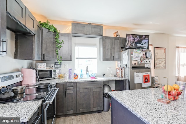 kitchen featuring light hardwood / wood-style floors, dark brown cabinetry, stainless steel appliances, and light stone countertops