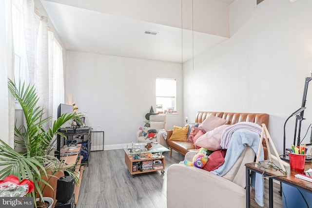 living room with visible vents, baseboards, and wood finished floors