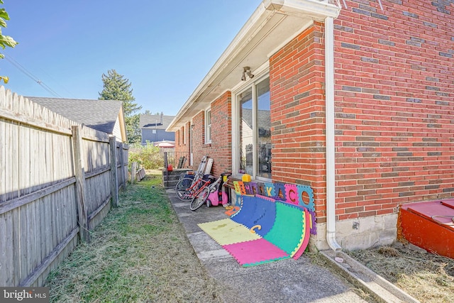 view of side of property featuring fence and brick siding