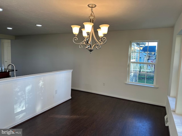 unfurnished room with dark wood-type flooring and an inviting chandelier