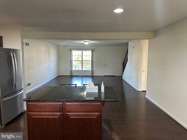 kitchen with a kitchen breakfast bar, a center island, dark wood-type flooring, and stainless steel refrigerator