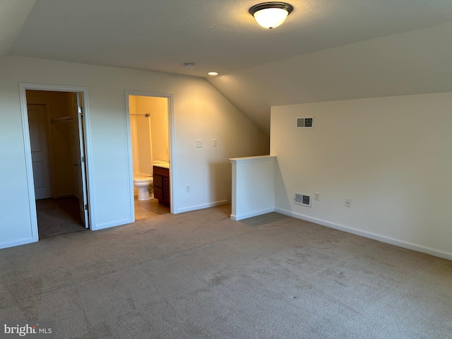 bonus room with lofted ceiling and light carpet