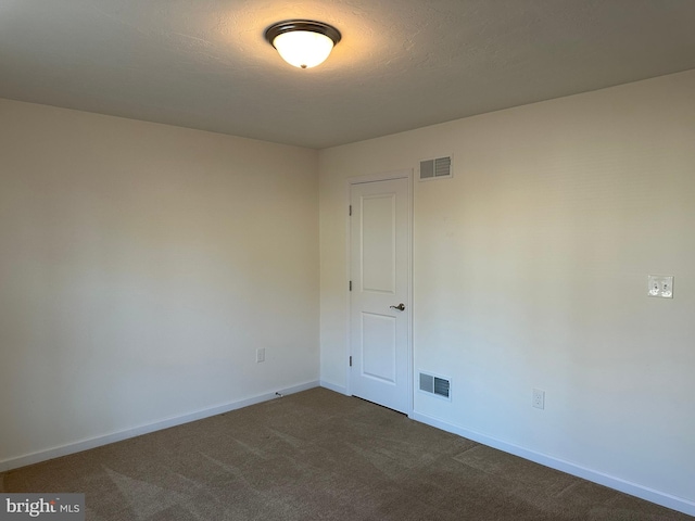 empty room featuring a textured ceiling and dark carpet