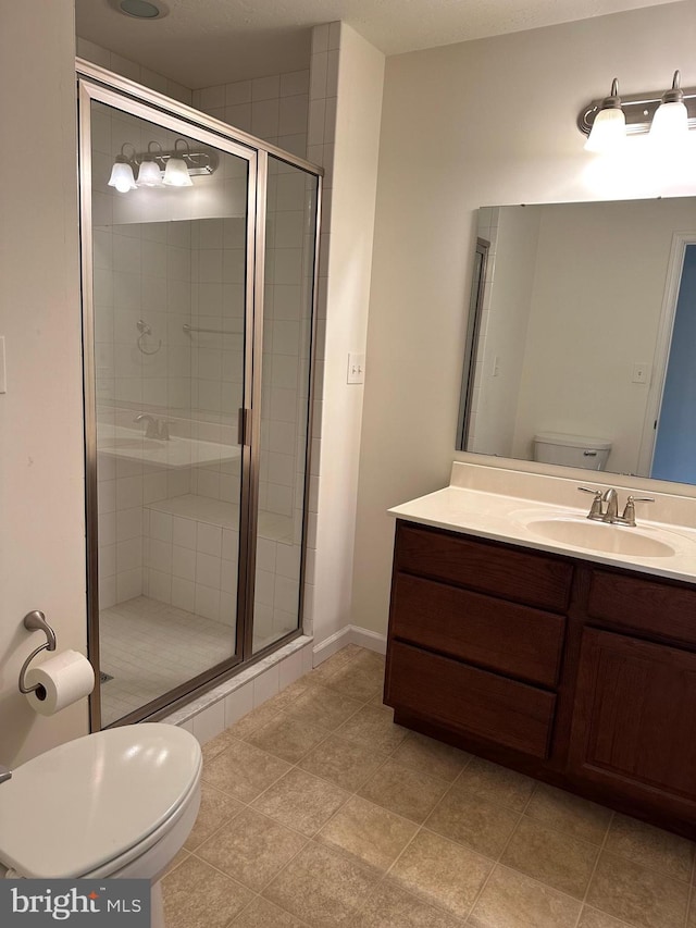 bathroom featuring toilet, tile patterned flooring, vanity, and a shower with door