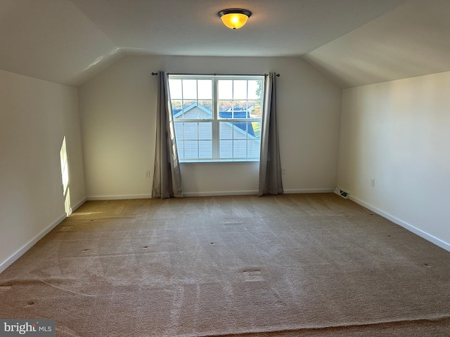 bonus room with lofted ceiling and light carpet