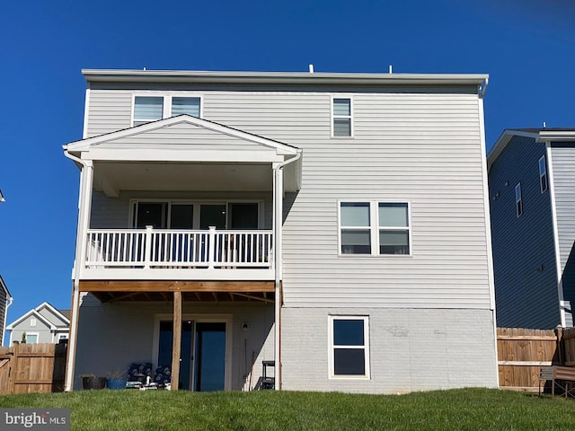 rear view of property with a balcony and a yard