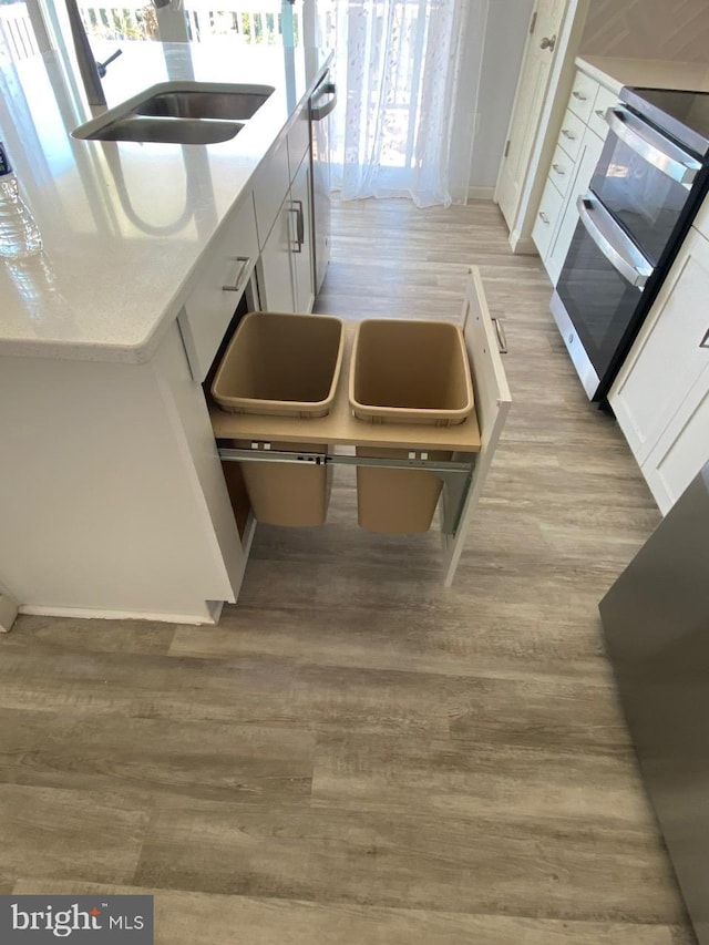 kitchen featuring light stone countertops, sink, light wood-type flooring, white cabinets, and appliances with stainless steel finishes