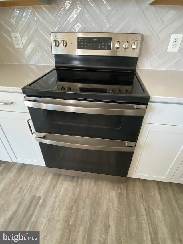 kitchen with electric range, light hardwood / wood-style floors, and white cabinetry