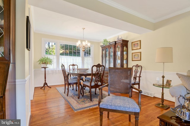 dining space featuring a chandelier, ornamental molding, and light wood-type flooring