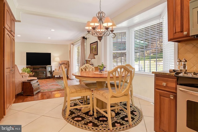 dining room featuring an inviting chandelier, ornamental molding, and light wood-type flooring