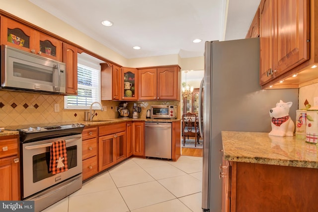 2123 Round Hill Rd, Fallston, MD 21047 - kitchen featuring stainless steel appliances, light stone counters, brown cabinets, a sink, and ornamental molding