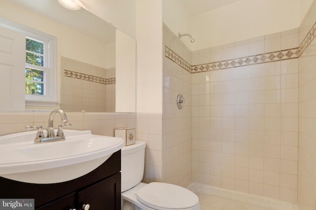 bathroom featuring a tile shower, vanity, tile walls, and toilet