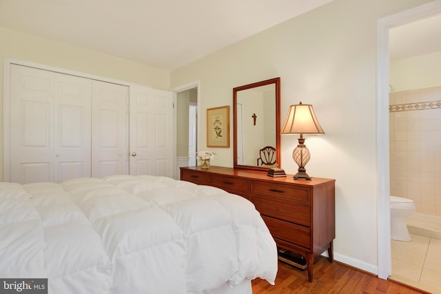 bedroom with ensuite bathroom, a closet, and light hardwood / wood-style floors