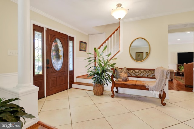 foyer featuring light tile patterned flooring, crown molding, and decorative columns