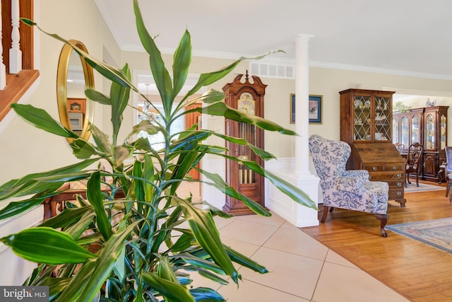 living area featuring decorative columns, light hardwood / wood-style flooring, and crown molding