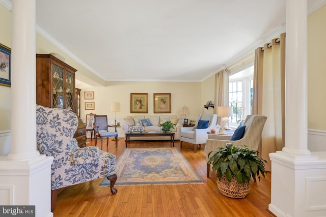 living room featuring decorative columns, wood-type flooring, and ornamental molding