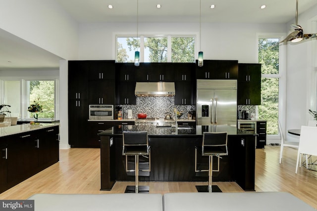 kitchen with a center island with sink, a kitchen bar, a healthy amount of sunlight, and appliances with stainless steel finishes