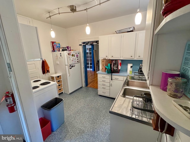 kitchen featuring hanging light fixtures, white fridge, and white cabinetry