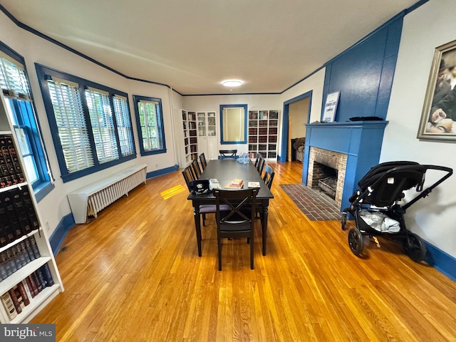 dining room with radiator, a fireplace, and hardwood / wood-style floors