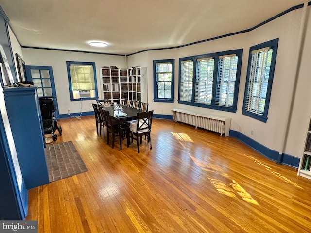 dining room featuring cooling unit, radiator, hardwood / wood-style flooring, and ornamental molding