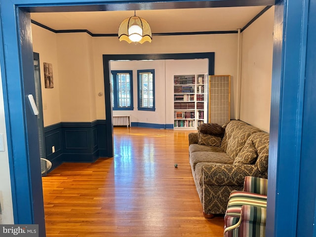 living room with light hardwood / wood-style floors, ornamental molding, and radiator